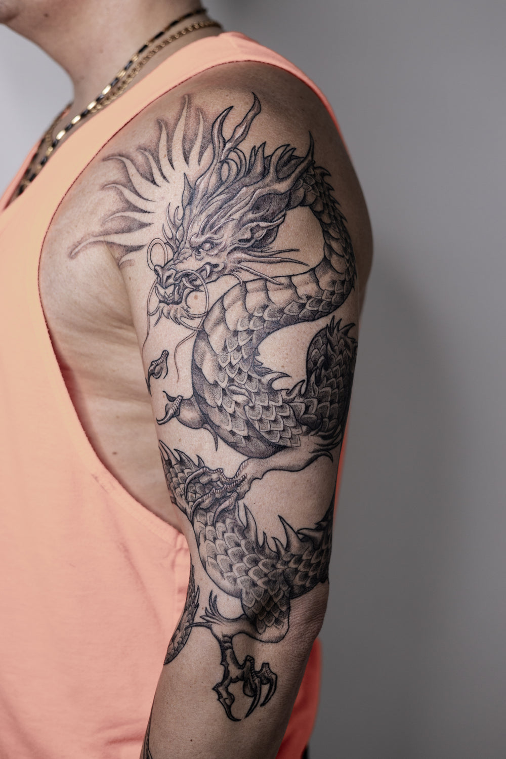 Dragon tattoo on a person's arm with a plain background