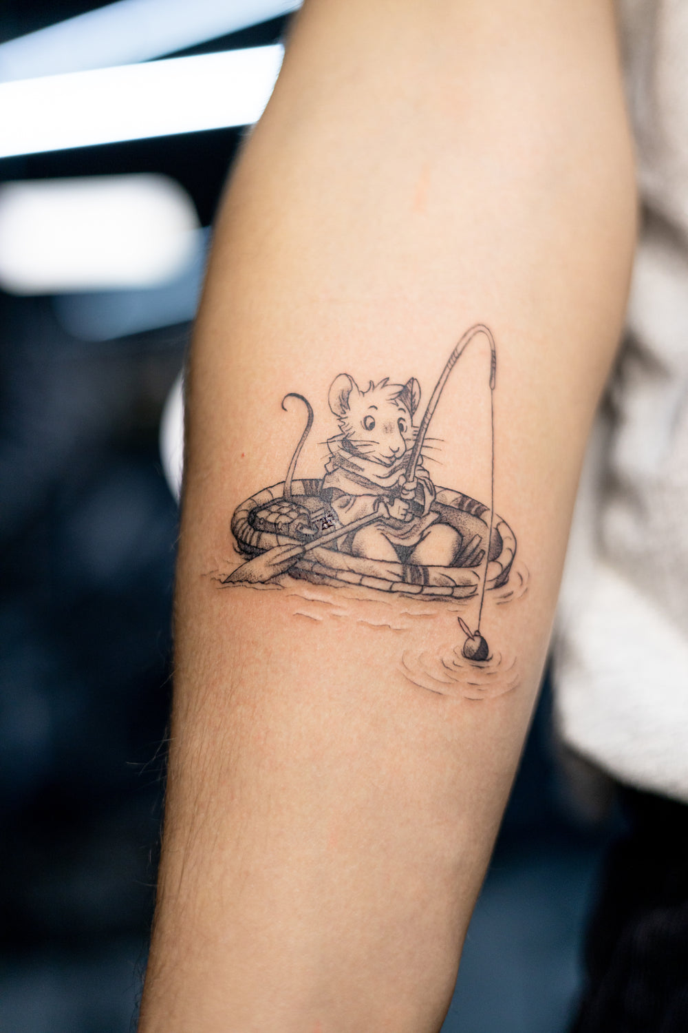 Tattoo of a mouse with a bow and arrow on a person's arm.