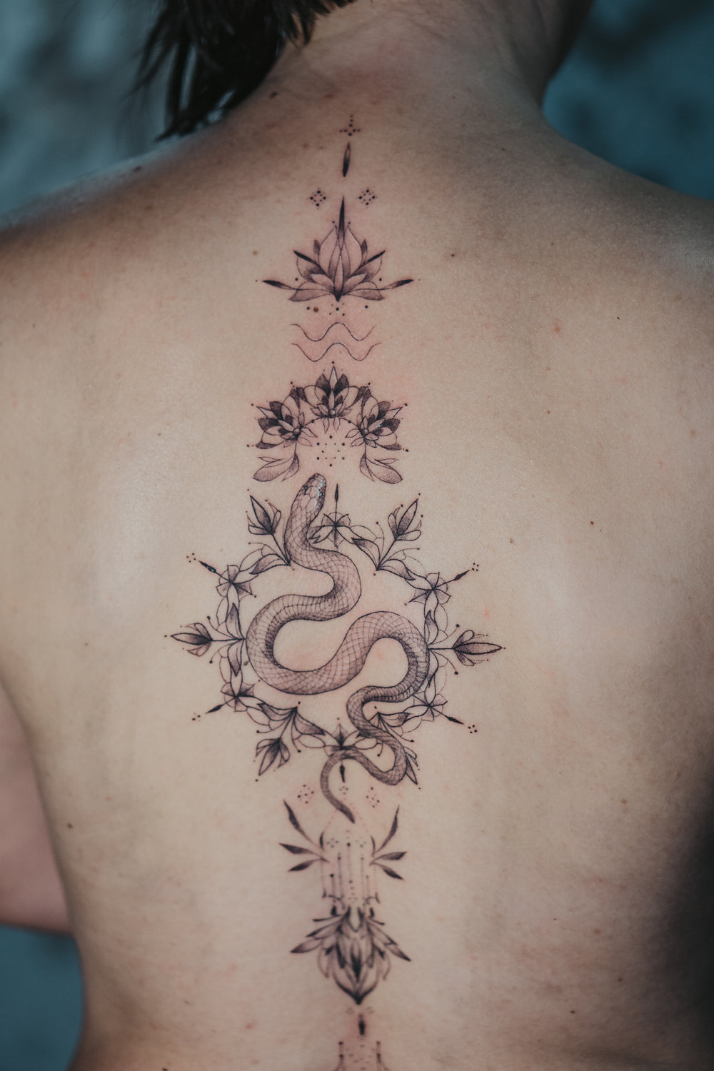 Tattoo of a snake and floral design on a person's back