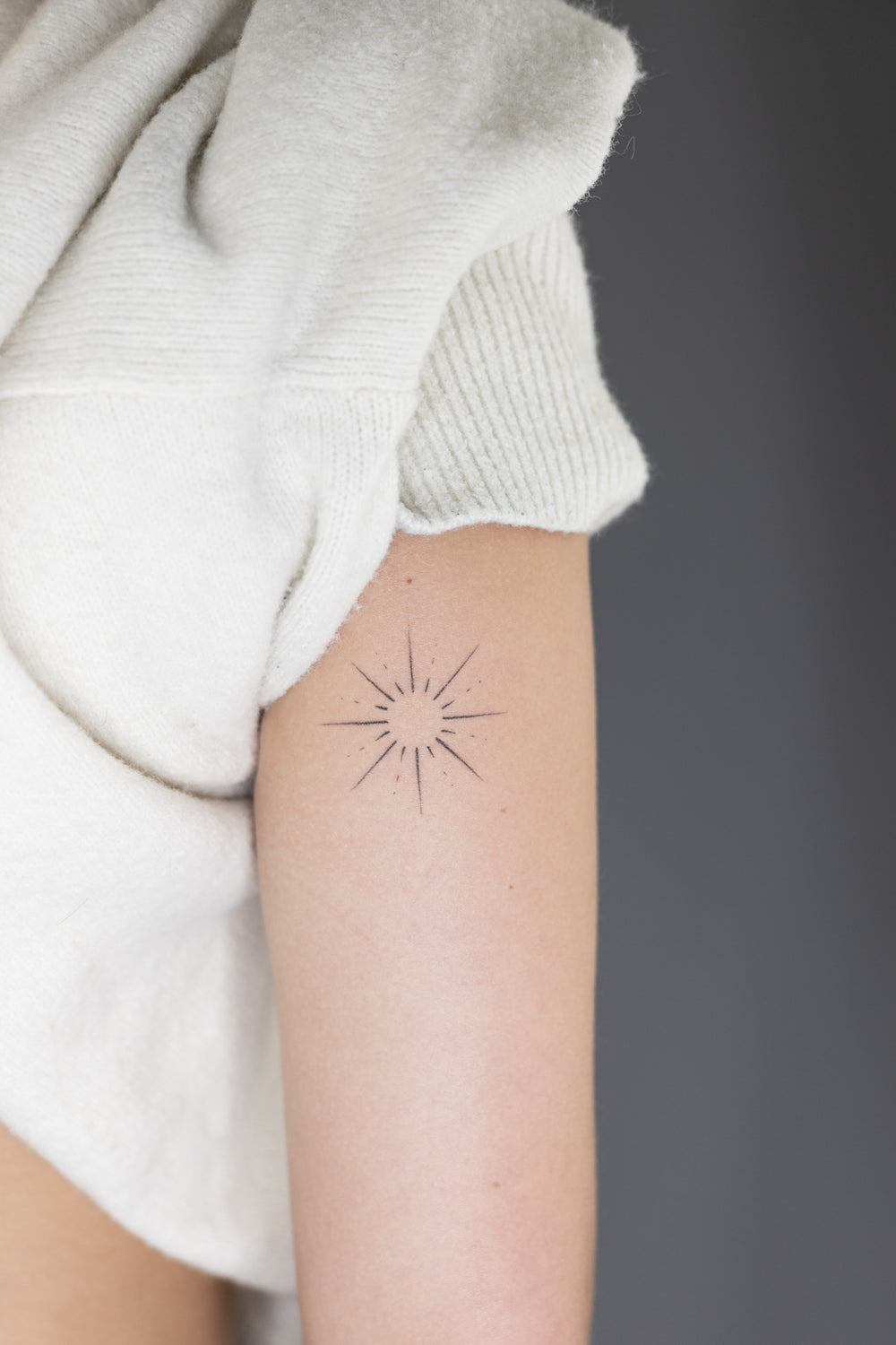 Small star tattoo on a person's arm with a neutral background
