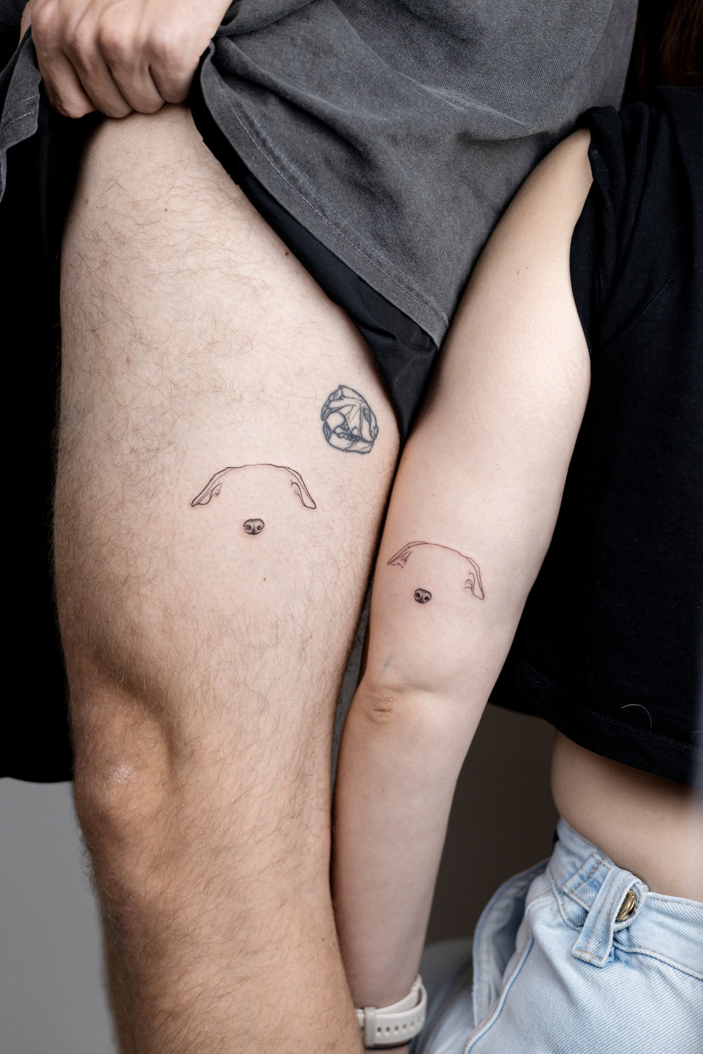 Two people with matching tattoos on their arms, sitting close together.