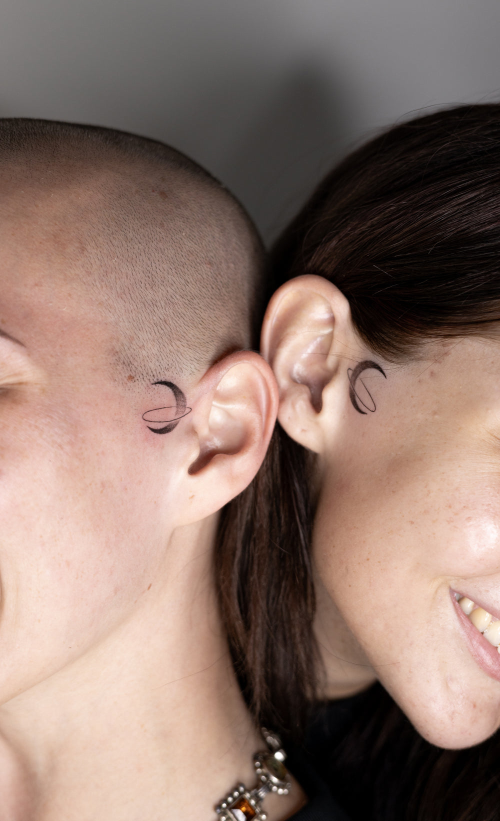 Two people with crescent moon tattoos on their ears.